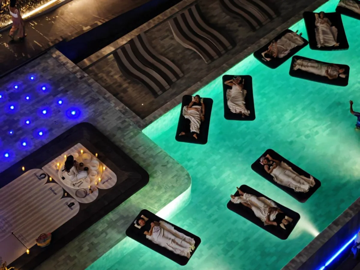 Guests floating on mats during a private pool sound bath at night